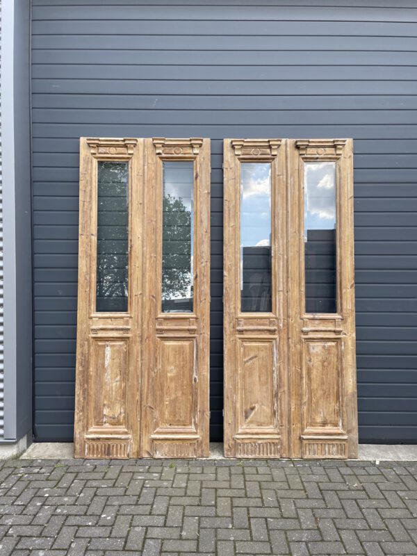 Antique double wooden doors with glass panels and intricate carvings, vooraanzicht.