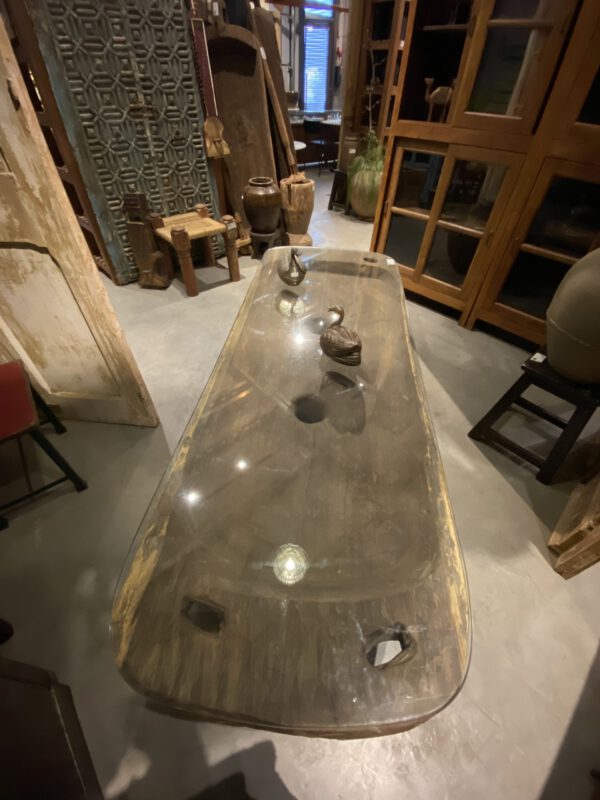 Vintage teakwood table with a smooth glass top and carved details, vooraanzicht.