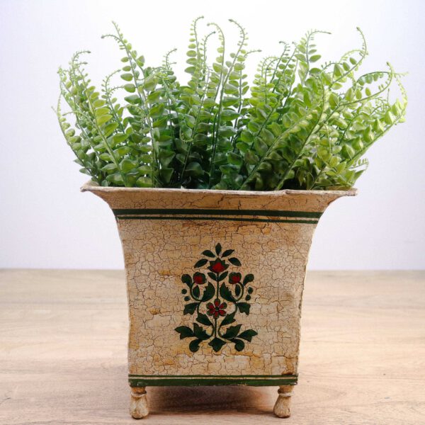 Rustic, vintage wooden planter with painted floral design and green faux ferns, vooraanzicht.